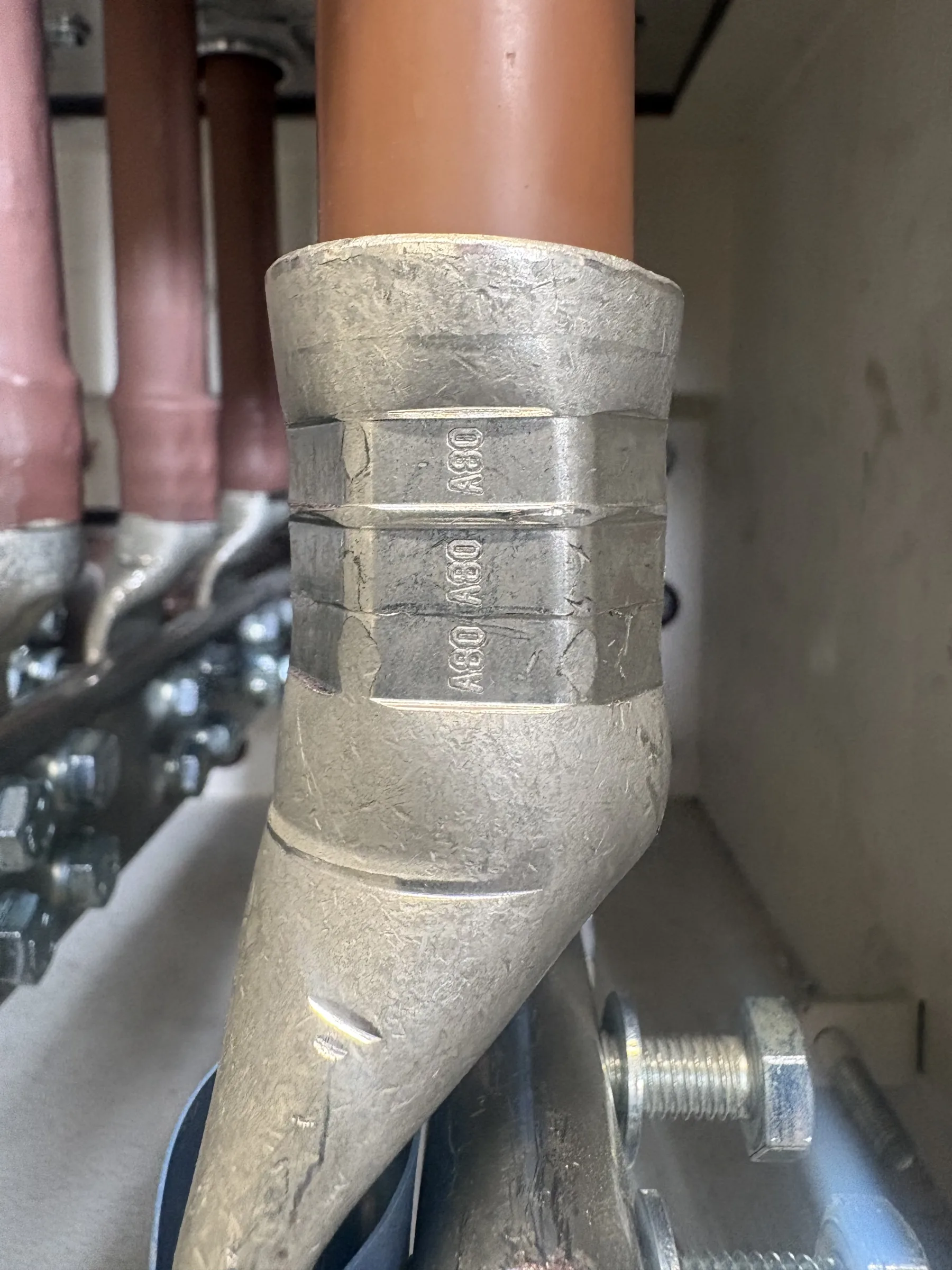 Close-up of a brown insulated cable fitted with a large silver-coloured metal connector and bolted terminal hardware.